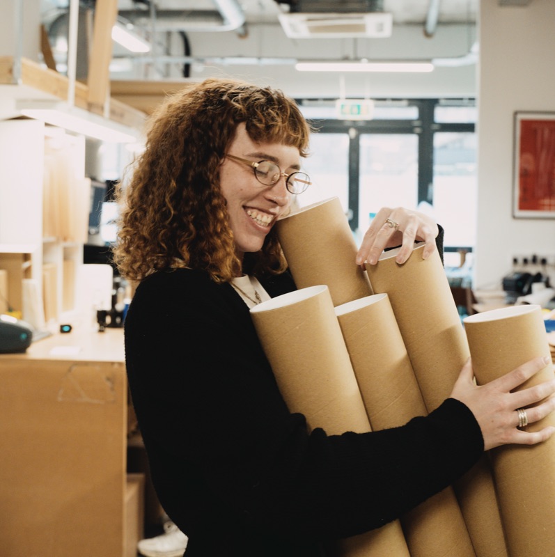 Membre de l'équipe transportant des tubes de tirages dans le studio theprintspace