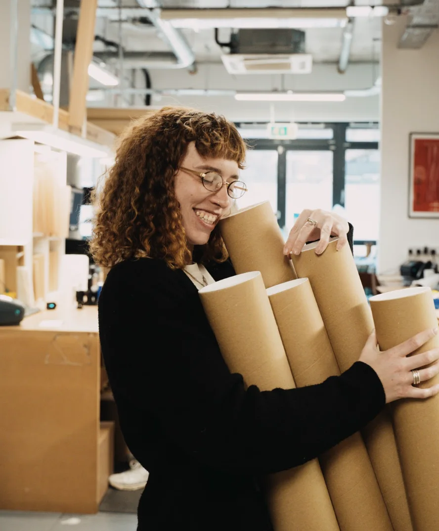 A member of our team carrying kraft postal tubes in the London studio