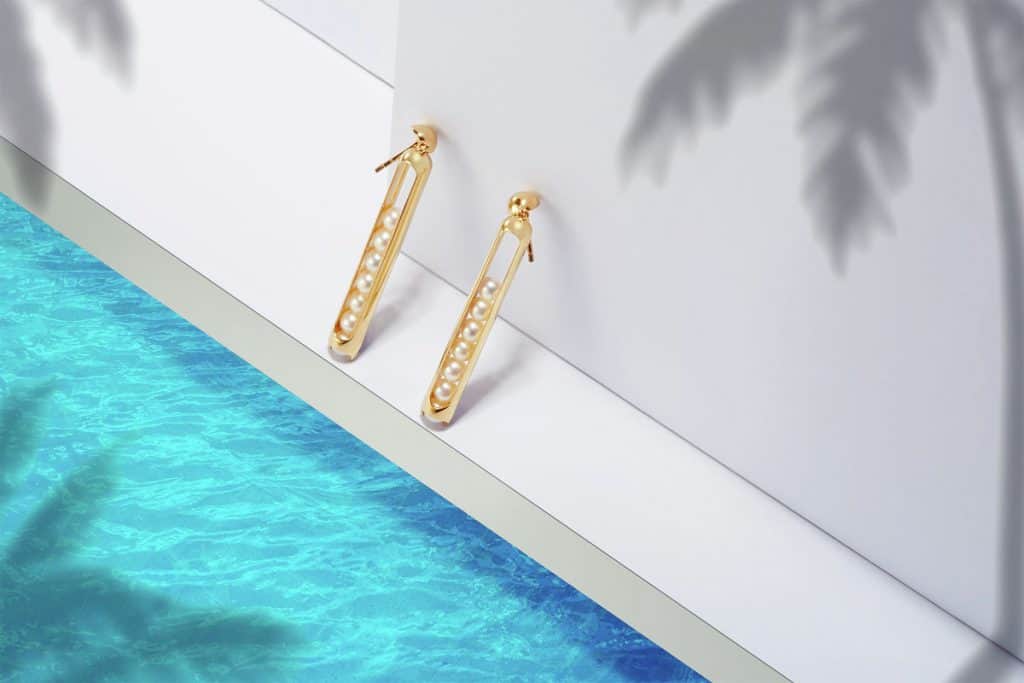 A pair of gold earrings photographed in a handmade miniature set depicting a swimming pool, by London-based product photographer Elio Ruscetta